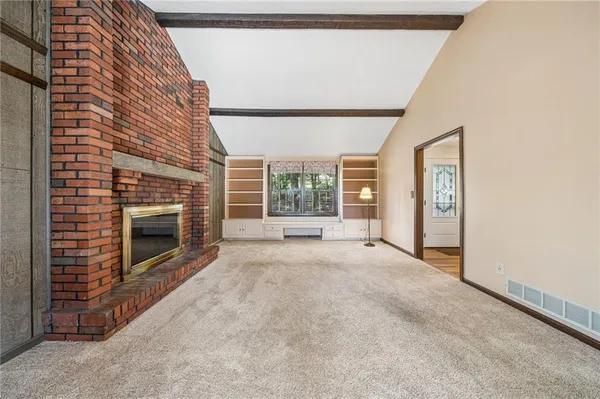 a view of an empty room with a fireplace and a window