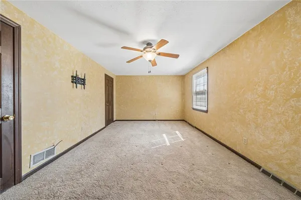 an empty room with windows and fan