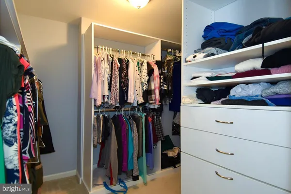 a view of walk in closet with clothes and shoes