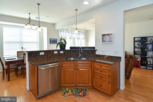 a kitchen with kitchen island granite countertop a sink cabinets and wooden floor