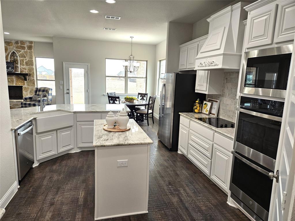 241 Blythe Road Van Alstyne, TX 75495 - Photo 3 of 37 a kitchen with stainless steel appliances kitchen island granite countertop a refrigerator oven a sink dishwasher and white cabinets with wooden floor
