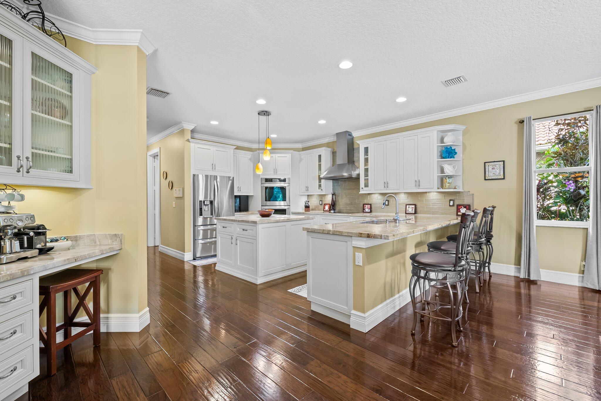 21167 Falls Ridge Way Boca Raton, FL 33428 - Photo 17 of 72 a kitchen with a table chairs wooden floors and white stainless steel appliances