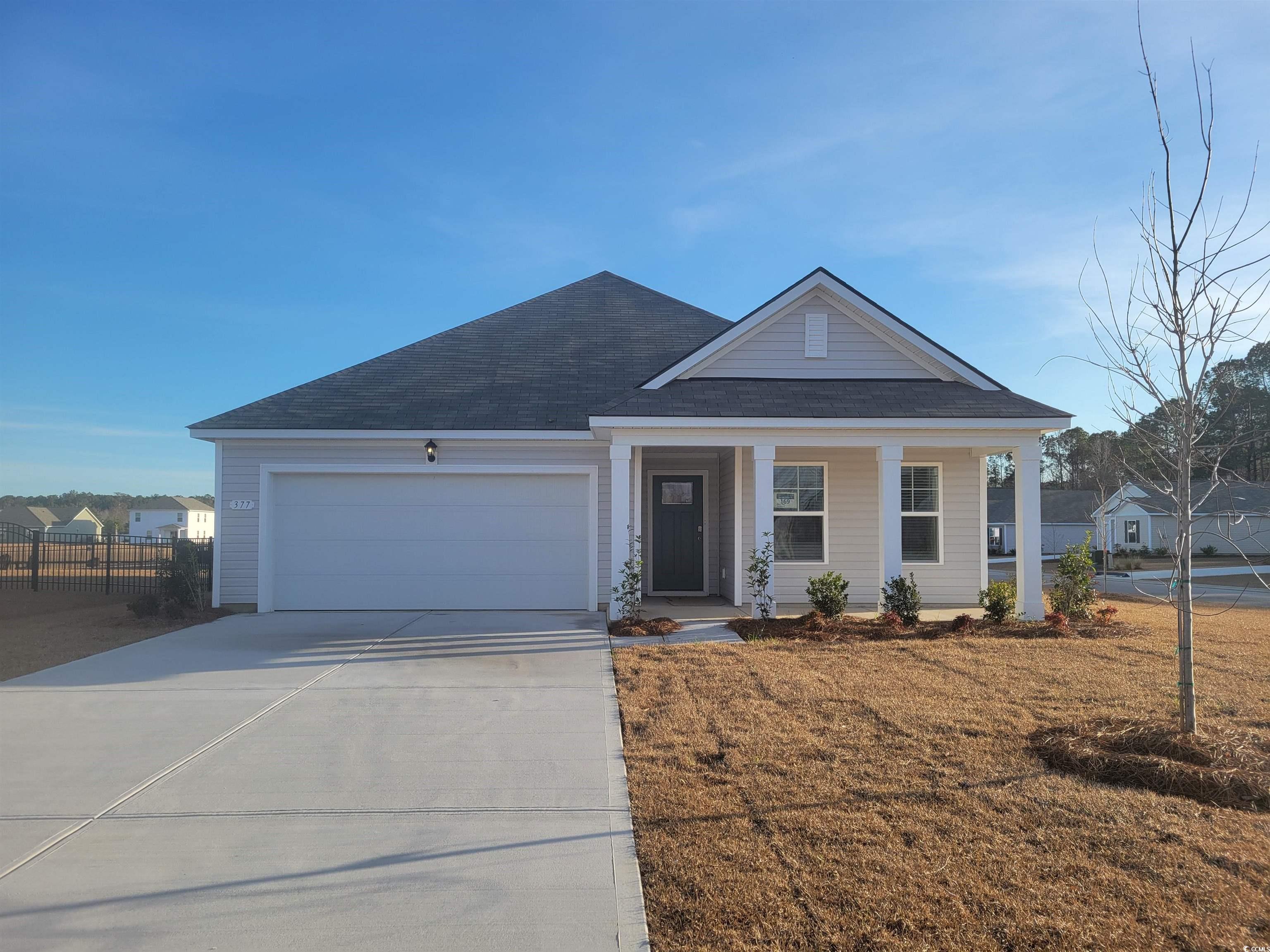 View of front facade with a porch, driveway, a garage, and roof with shingles
