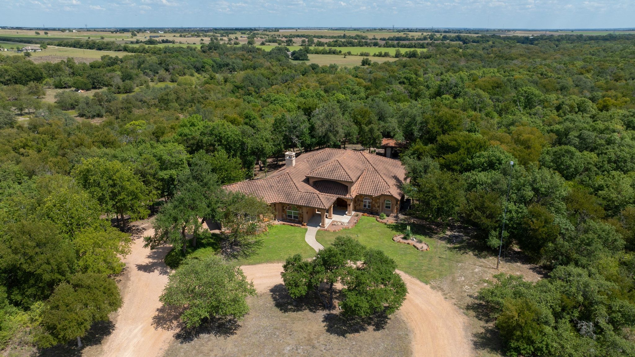 Aerial view of property and surrounding area with a heavily wooded area