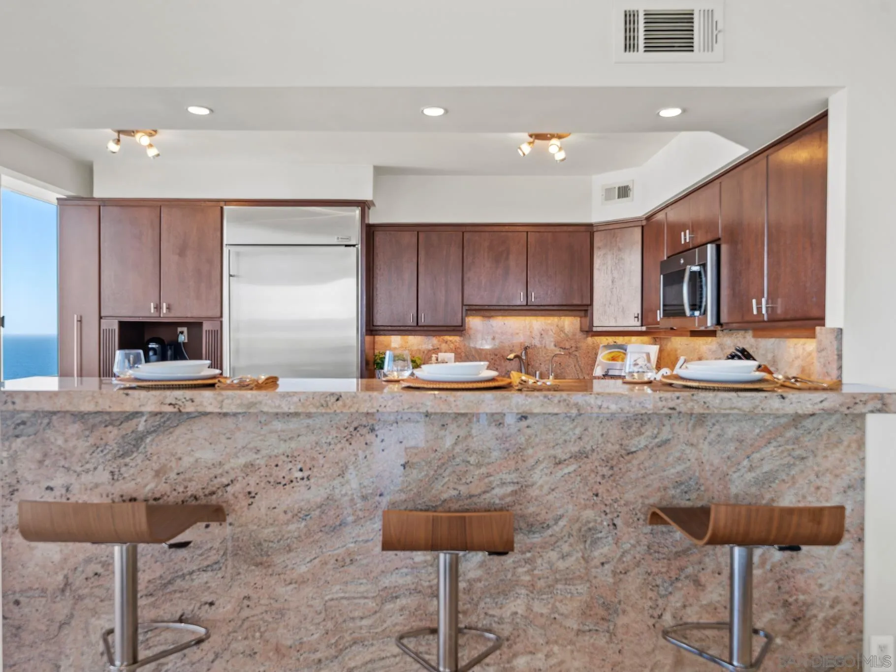 1730 Avenida Del Mundo, Unit 1503 Coronado, CA 92118 - Photo 11 of 47 a large kitchen with stainless steel appliances granite countertop a stove a sink a oven with a dining table and chair