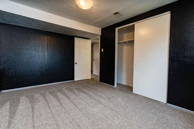 a view of an empty room with closet and a window