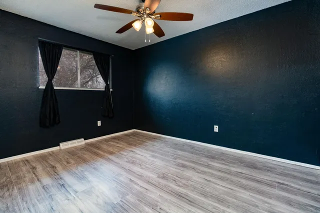 a view of an empty room with a window and wooden floor