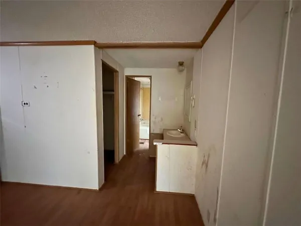 a view of a hallway with wooden floor and a cabinet