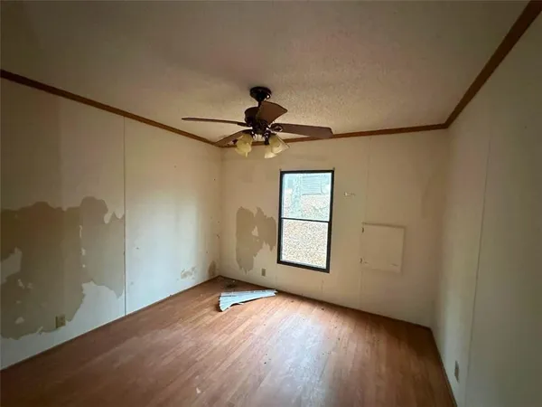 an empty room with wooden floor chandelier fan and windows