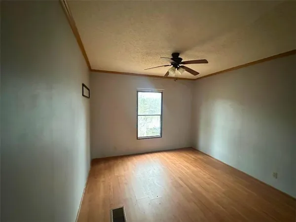 an empty room with a window and a ceiling fan