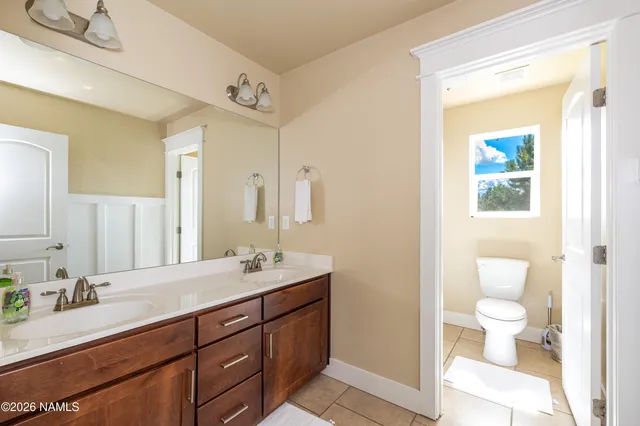 a bathroom with a double vanity sink toilet and a mirror