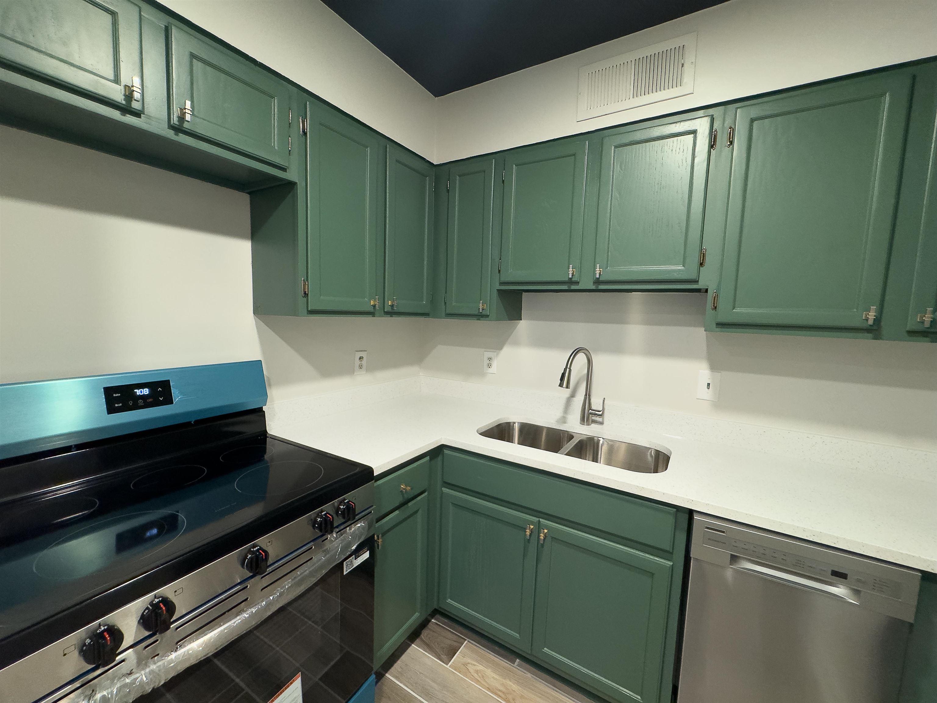 109 North Main Street, Unit 907 Memphis, TN 38103 - Photo 20 of 29 Kitchen featuring green painted cabinetry, white countertops, a stainless steel double basin sink with a high-arc faucet, and stainless steel appliances