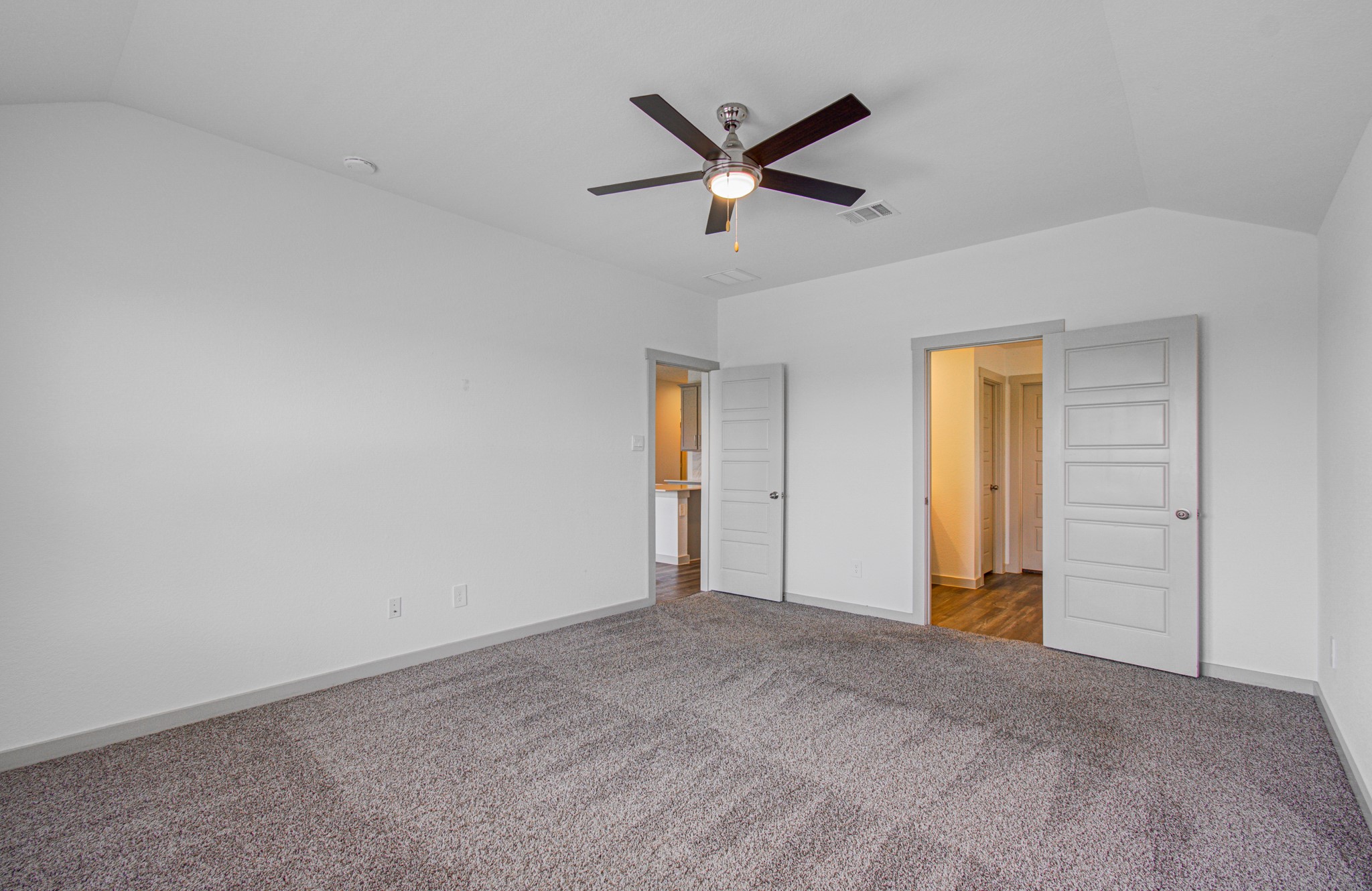 7903 Wrangler Shack Lane Rosharon, TX 77583 - Photo 24 of 29 This bright, spacious bedroom features neutral carpeting, a ceiling fan, and two convenient doors to a bathroom and hallway, blending comfort with functionality.