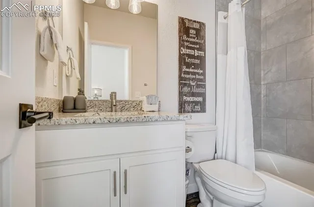 a bathroom with a granite countertop toilet sink and mirror