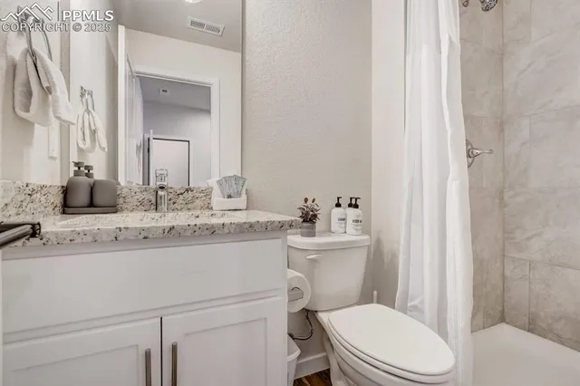 a bathroom with a granite countertop toilet sink vanity and mirror
