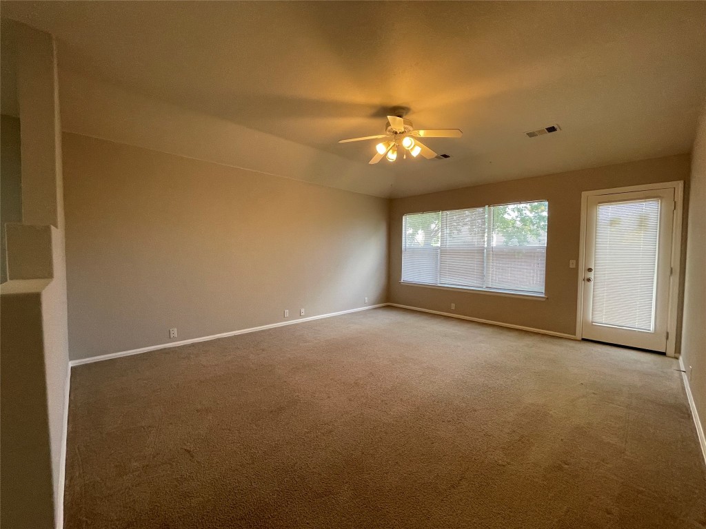 208 Spruce Drive Kyle, TX 78640 - Photo 8 of 26 an empty room with windows and chandelier fan