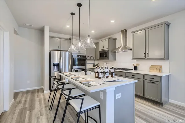 a kitchen with stainless steel appliances kitchen island granite countertop a sink a stove a refrigerator and island with wooden floor