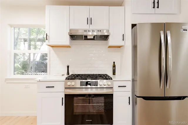 a kitchen with stainless steel appliances white cabinets and a refrigerator