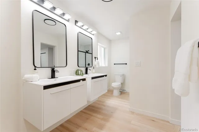 a bathroom with a double vanity sink mirror and toilet