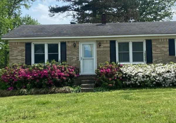 a view of a house with a flower garden in front of main door