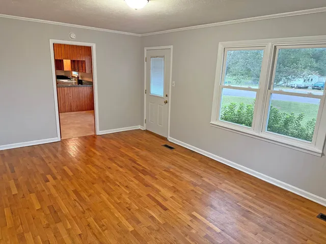 a view of an empty room with wooden floor and a window