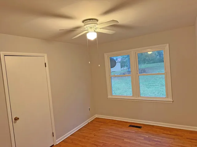 a view of an empty room with wooden floor and a window
