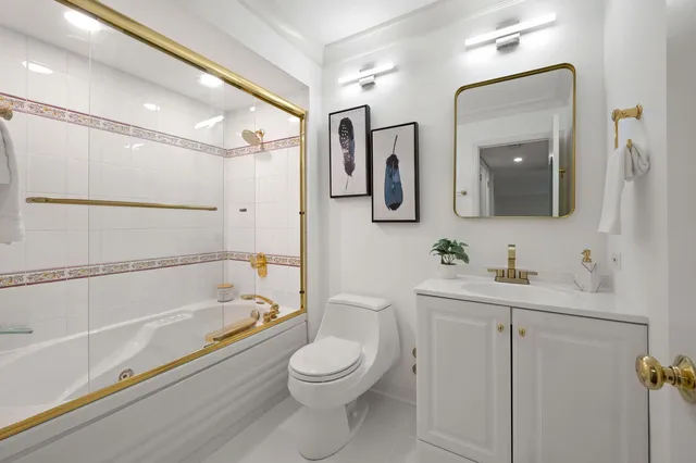 a bathroom with a toilet a sink a mirror a bathtub and vanity