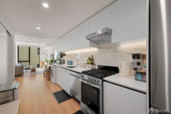 a kitchen with stainless steel appliances a stove a sink dishwasher and cabinets with wooden floor