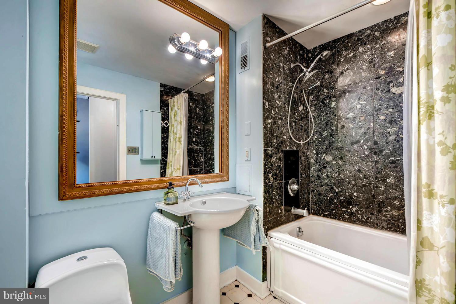 5106 North Franklintown Road Baltimore, MD 21207 - Photo 11 of 22 a bathroom with a sink a toilet a mirror a bathtub and shower