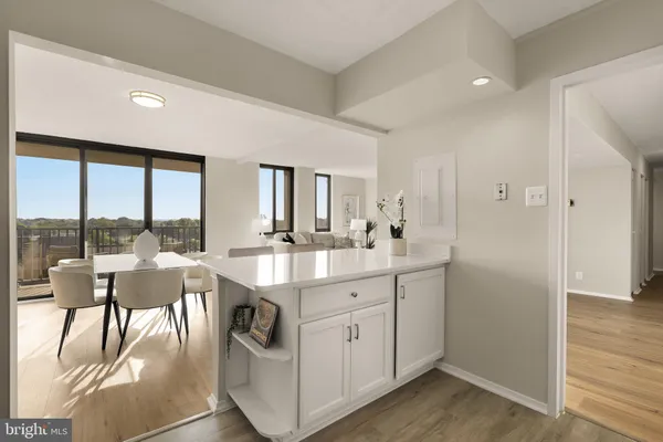 a open kitchen with a sink and white cabinets with wooden floor