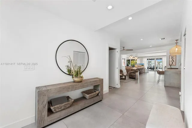 a living room with furniture a mirror and a view of kitchen