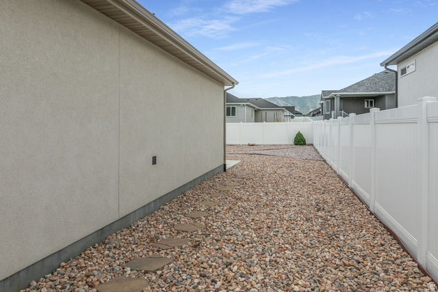 1228 North Providence Way Tooele, UT 84074 - Photo 24 of 28 Side yard featuring a gravel surface, stepping stone path, and white vinyl privacy fencing