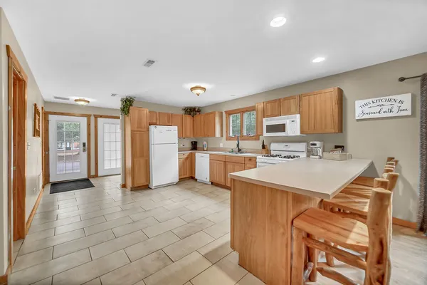 a large white kitchen with a sink a refrigerator and a stove top oven