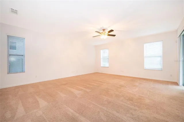 an empty room with windows and ceiling fan
