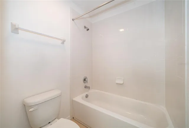 a white bath tub sitting next to a white toilet and vanity