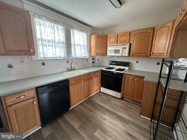 a kitchen with stainless steel appliances granite countertop wooden cabinets a sink a stove a refrigerator and dishwasher with wooden floor