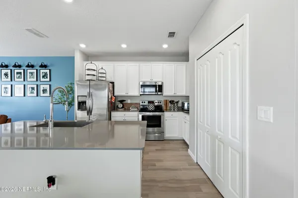a kitchen with stainless steel appliances granite countertop a refrigerator oven a sink dishwasher and white cabinets with wooden floor