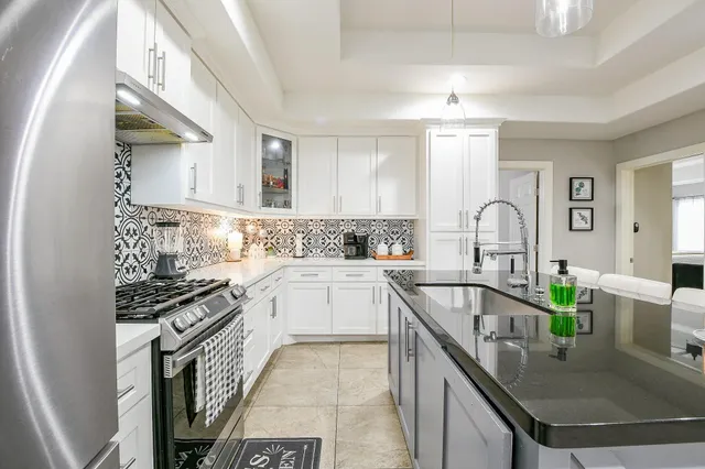 a kitchen with granite countertop a sink a counter top space cabinets and stainless steel appliances