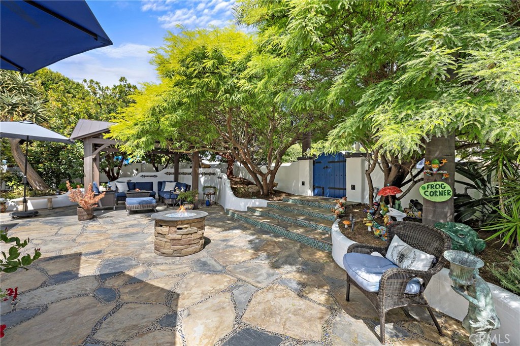 490 Agate Street Laguna Beach, CA 92651 - Photo 4 of 38 a view of a backyard with table and chairs potted plants and a large tree