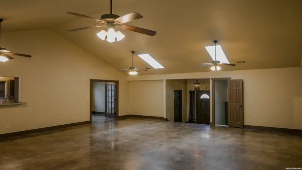 a view of an empty room with chandelier fan