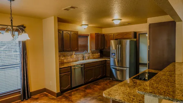 a kitchen with stainless steel appliances granite countertop a refrigerator and a sink