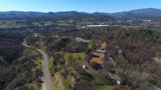 an aerial view of residential house with green field and mountains