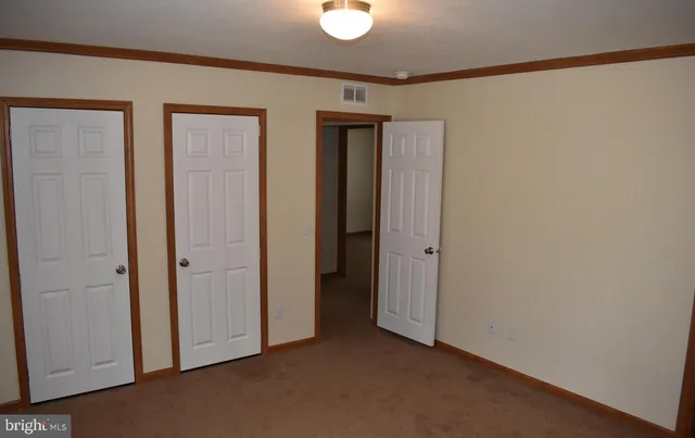 a view of an empty room with closet and a window