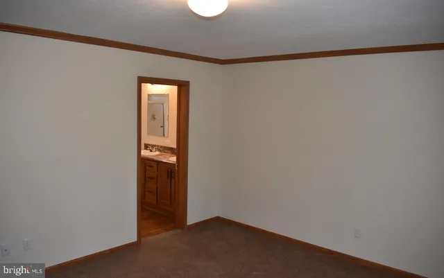 a view of an empty room with wooden floor and closet