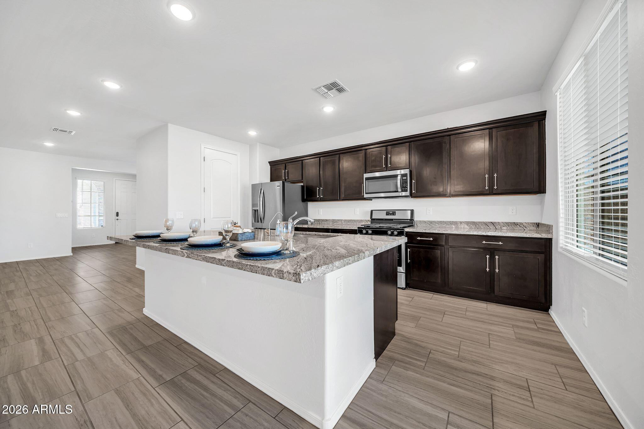 14384 West Hearn Road Surprise, AZ 85379 - Photo 14 of 63 a kitchen with stainless steel appliances kitchen island granite countertop a stove a sink and a refrigerator