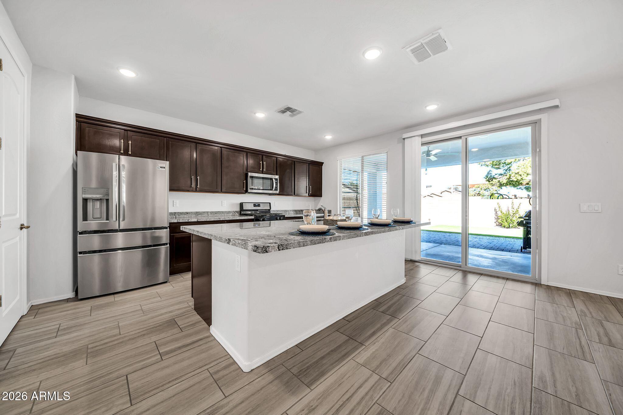 14384 West Hearn Road Surprise, AZ 85379 - Photo 15 of 63 a kitchen with stainless steel appliances granite countertop a refrigerator a sink dishwasher a stove and a refrigerator with wooden floor