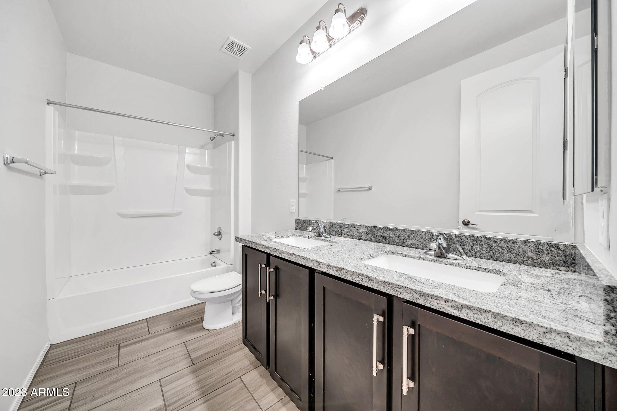 14384 West Hearn Road Surprise, AZ 85379 - Photo 32 of 63 a bathroom with a granite countertop sink mirror vanity and toilet