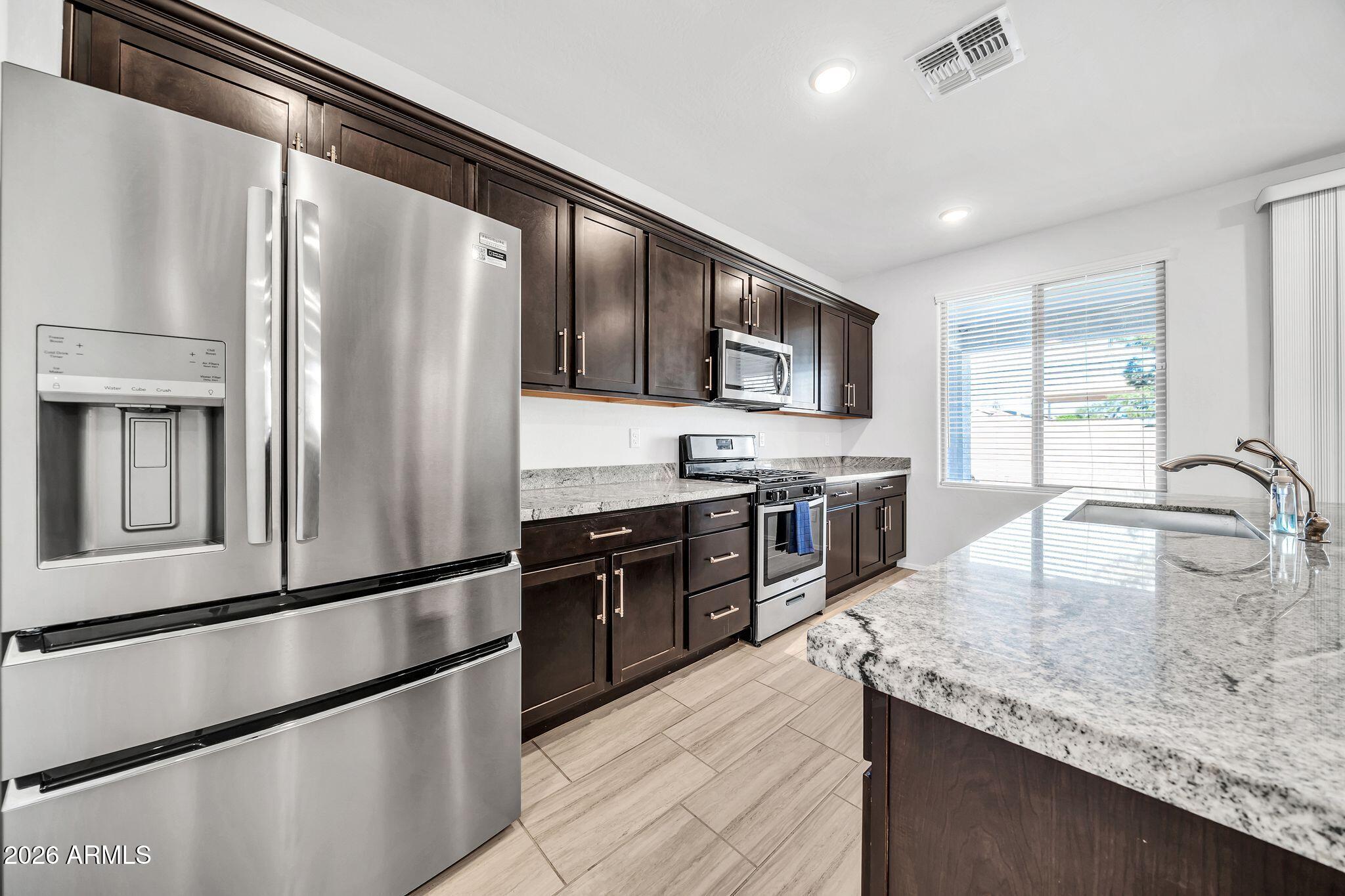 14384 West Hearn Road Surprise, AZ 85379 - Photo 9 of 63 a kitchen with granite countertop stainless steel appliances and wooden cabinets