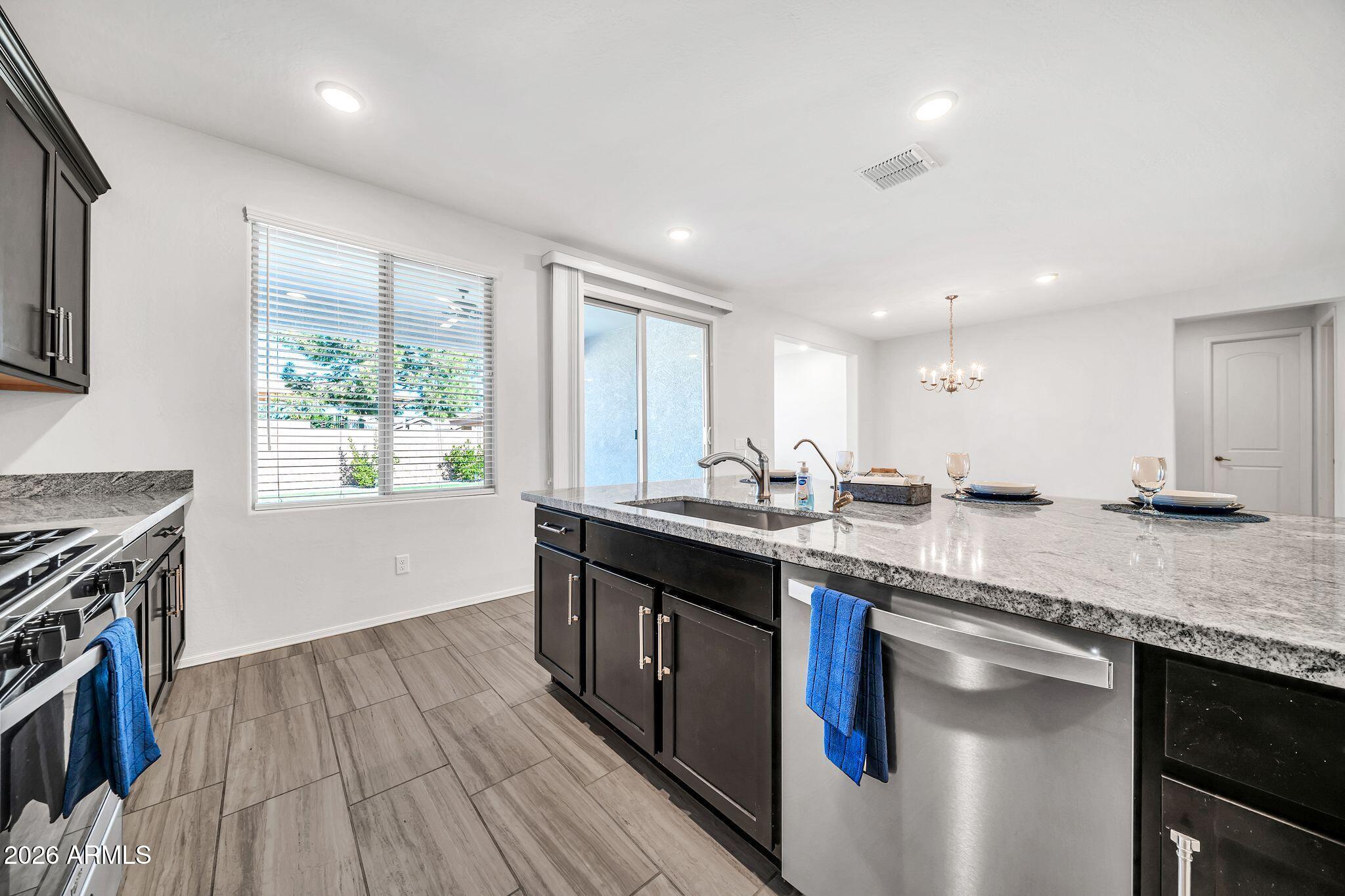 14384 West Hearn Road Surprise, AZ 85379 - Photo 10 of 63 a kitchen with stainless steel appliances granite countertop a sink stove and wooden floor