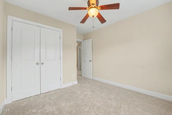 an empty room with closet and fan